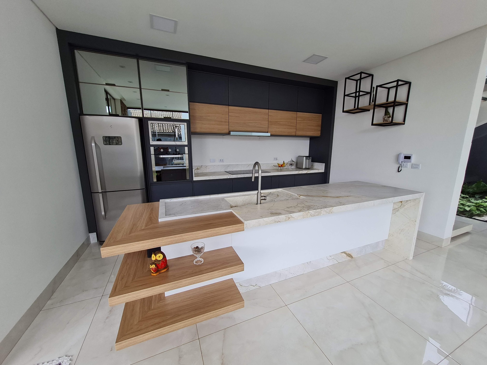 Cozinha planejada com ilha em pedra e detalhes em madeira